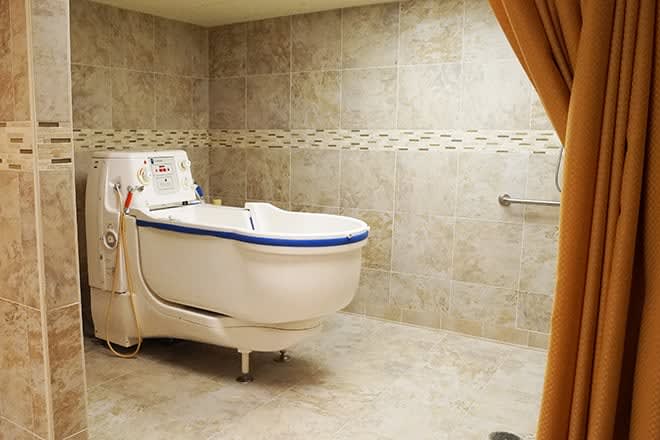 A spacious bathroom equipped with a specialized bathtub designed for healthcare needs.