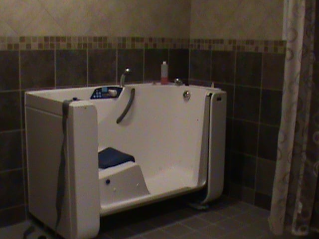 A walk-in bathtub in a tiled bathroom designed for accessibility.
