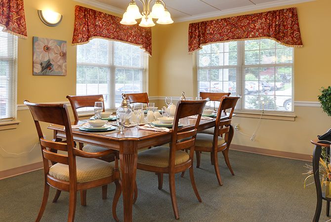 A well-set dining room with a wooden table and chairs, illuminated by overhead lights.