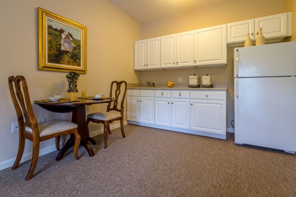 A cozy kitchen and dining area with white cabinets, a round wooden table, and chairs.