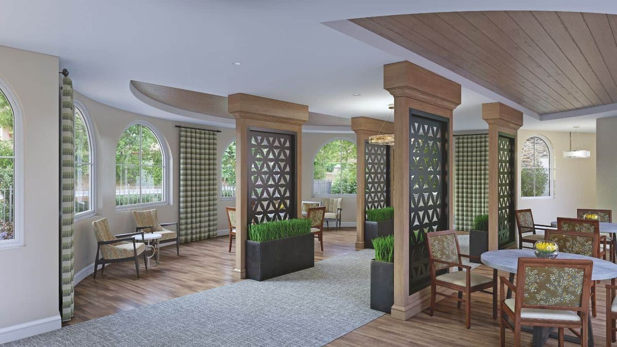 A modern restaurant interior featuring wooden elements, partition walls with geometric patterns, and green plants.