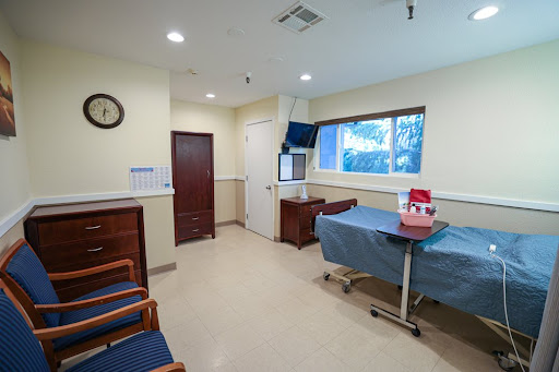 A clean and organized hospital room with a bed, patient amenities, and natural light.