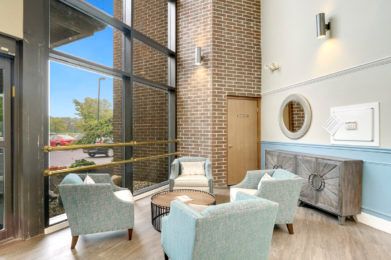 A modern lobby area featuring comfortable seating and large windows that flood the space with natural light.