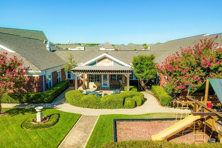 A well-maintained residential building with a landscaped garden and patio on a sunny day.