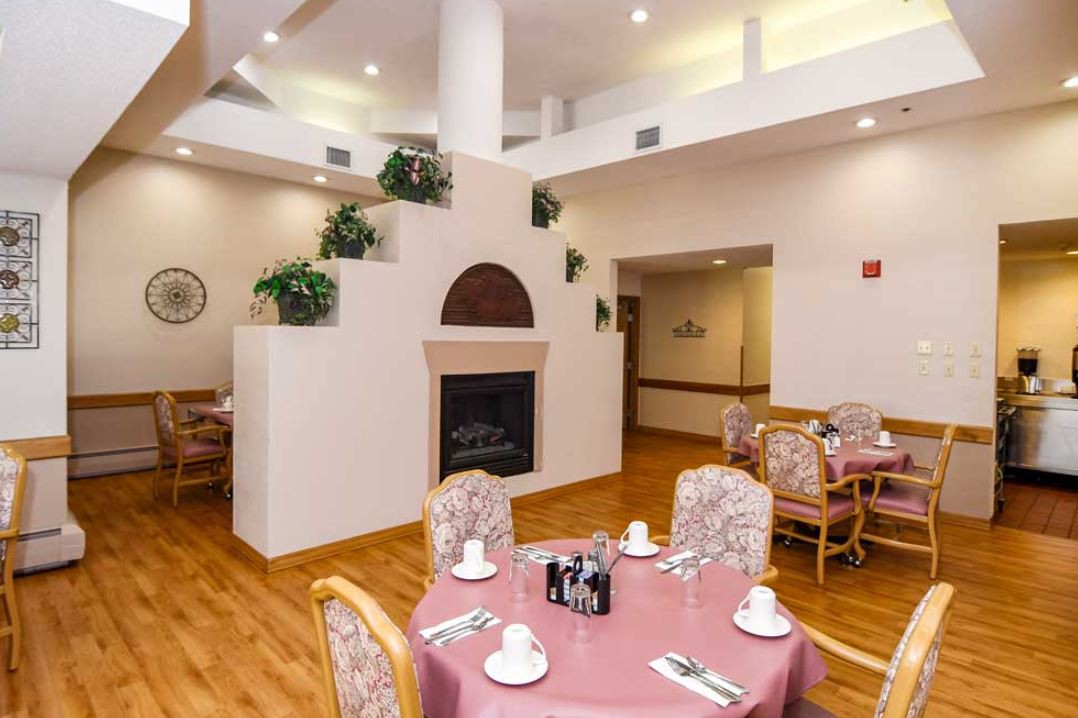 A cozy dining area with elegantly set tables and a decorative fireplace.