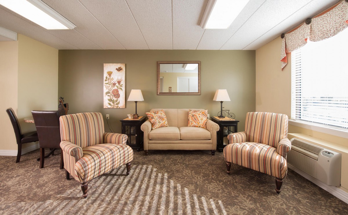 A cozy living room with striped armchairs, a sofa, and elegant lighting.
