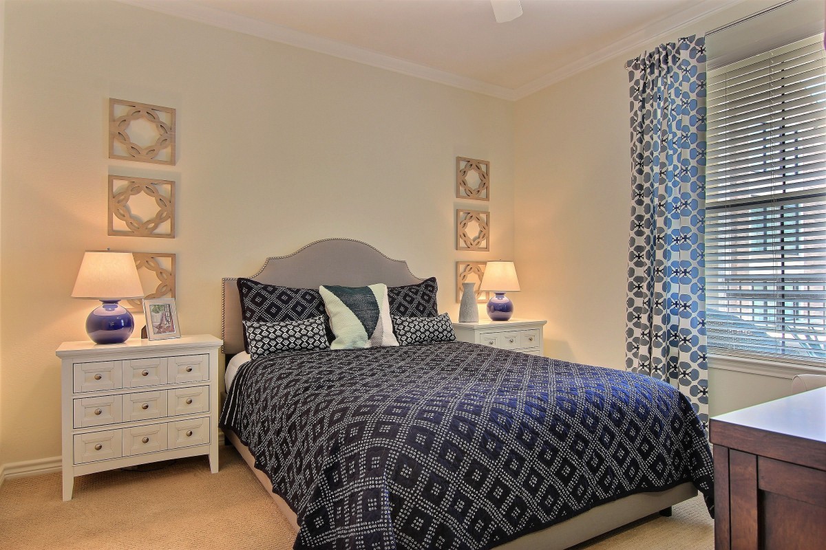 A cozy bedroom with a patterned bedspread and curtains, complemented by matching nightstands and lamps.