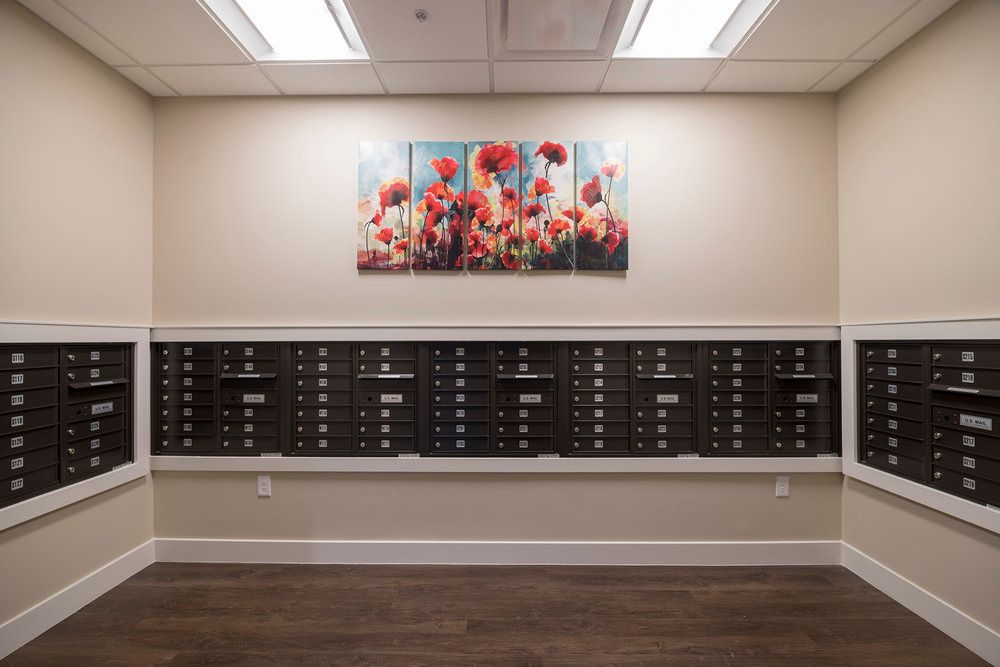 A hallway with rows of mailboxes below a vibrant floral artwork.