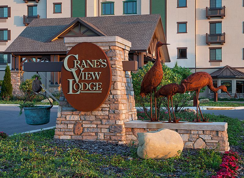 A view of the Grands View Lodge sign with ornamental landscaping and building in the background.