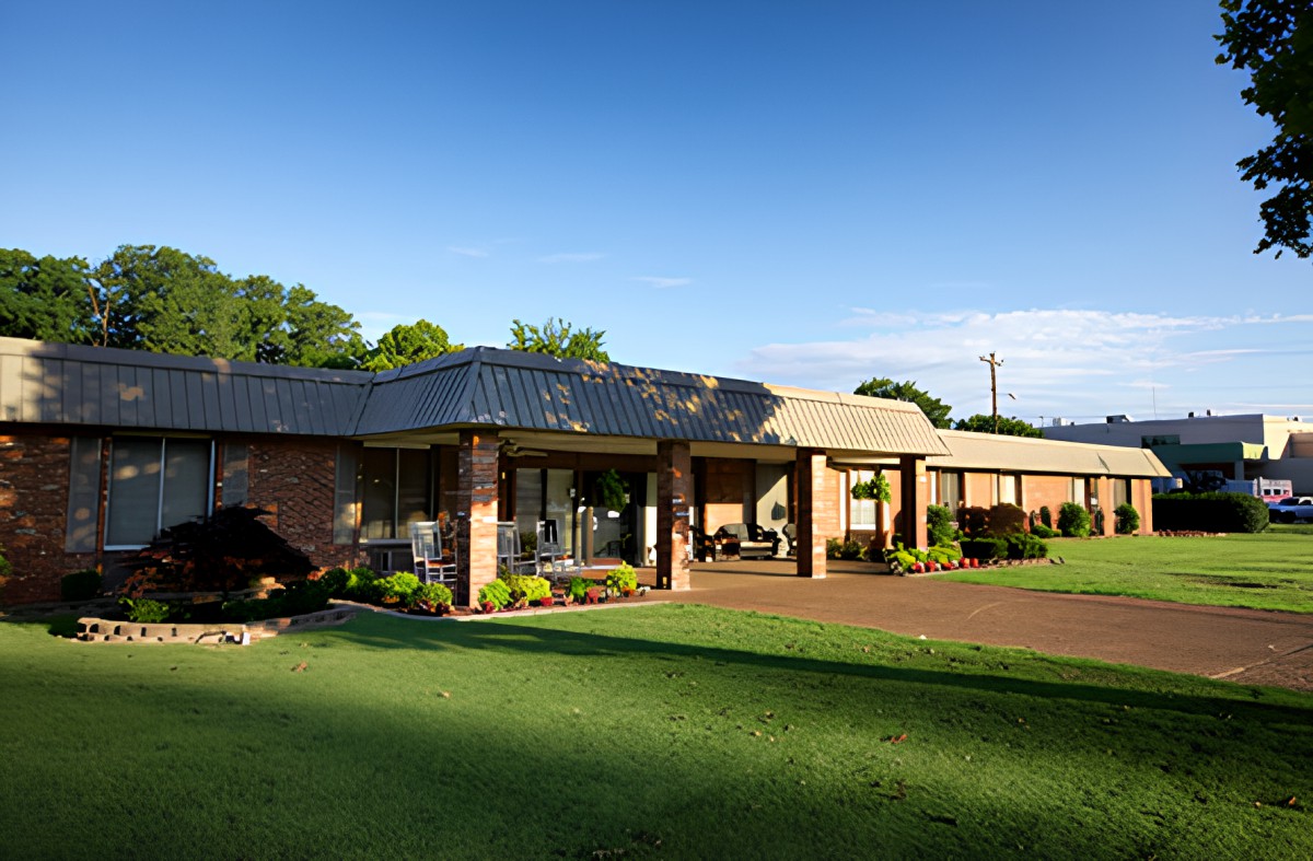 A brick hotel building with a well-maintained lawn and clear blue sky.