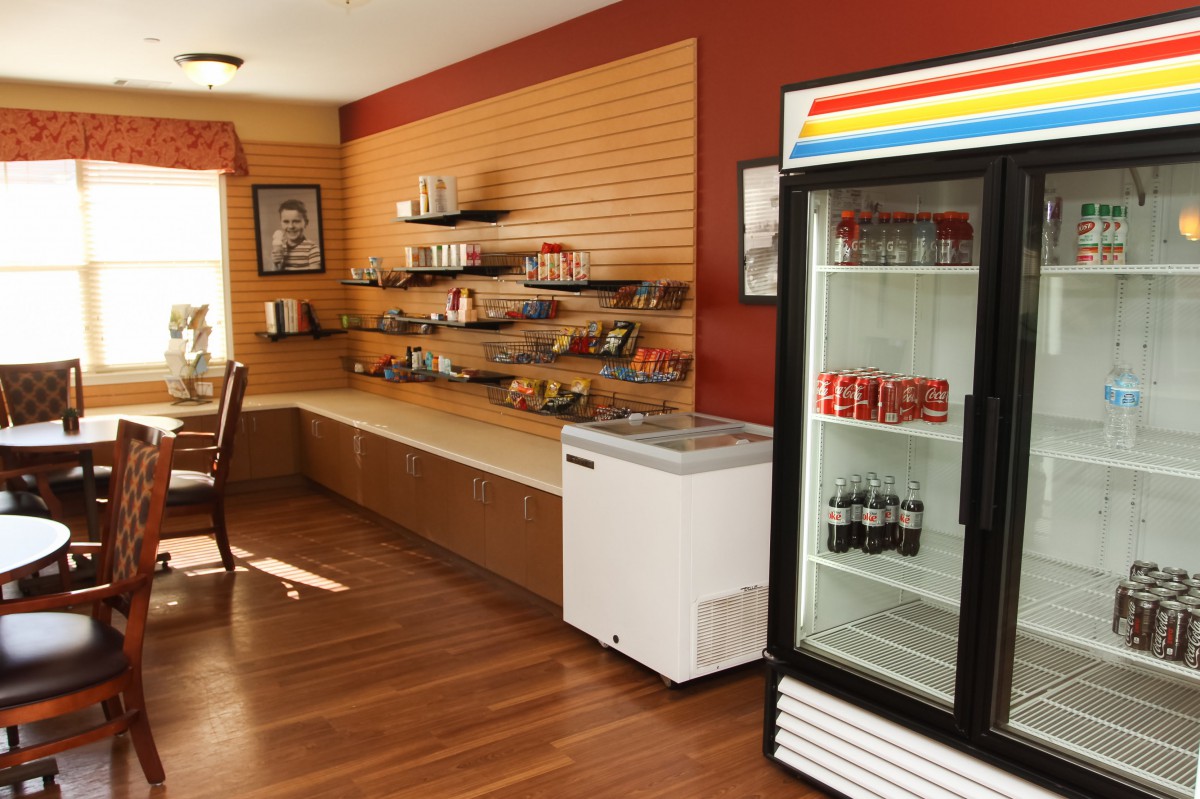 A small snack area with shelves stocked with snacks and a fridge containing drinks.