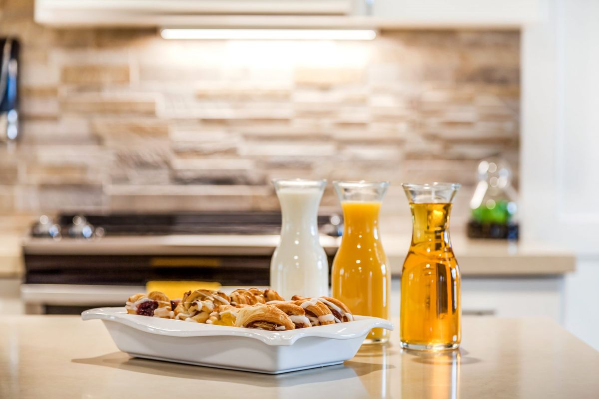 A breakfast setup featuring pastries with carafes of milk and orange juice in a kitchen.