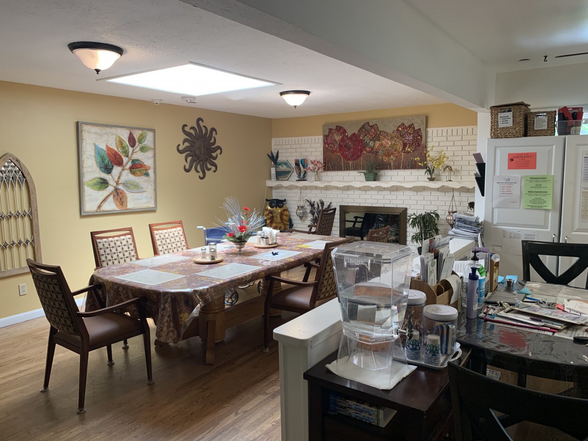 A cozy dining area with a table set, artwork on the walls, and a view into the kitchen.