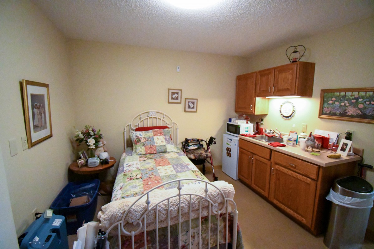 A compact bedroom featuring a single bed and a kitchenette.