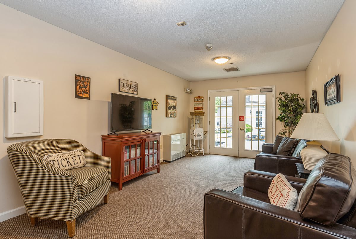 A cozy living room with comfortable seating and a large television, decorated with various wall art and accessories.