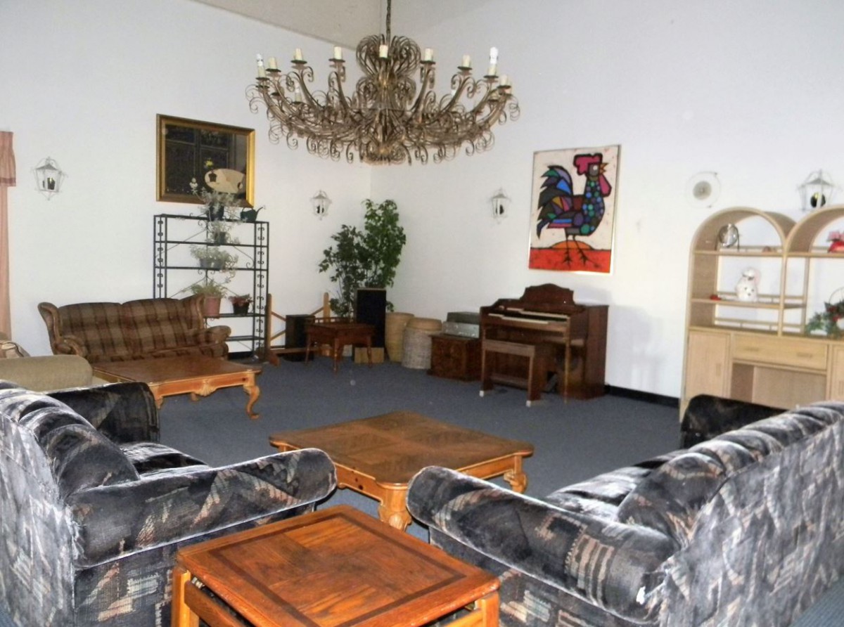 A spacious living room with a grand chandelier, multiple sofas, and a piano.