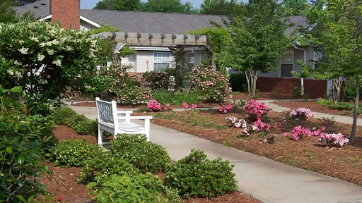 A serene garden area featuring vibrant flowers and a welcoming bench along a pathway.