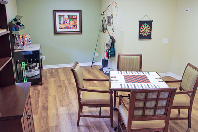 A cozy room featuring a table with chairs, a dartboard on the wall, and a fishing rod corner.