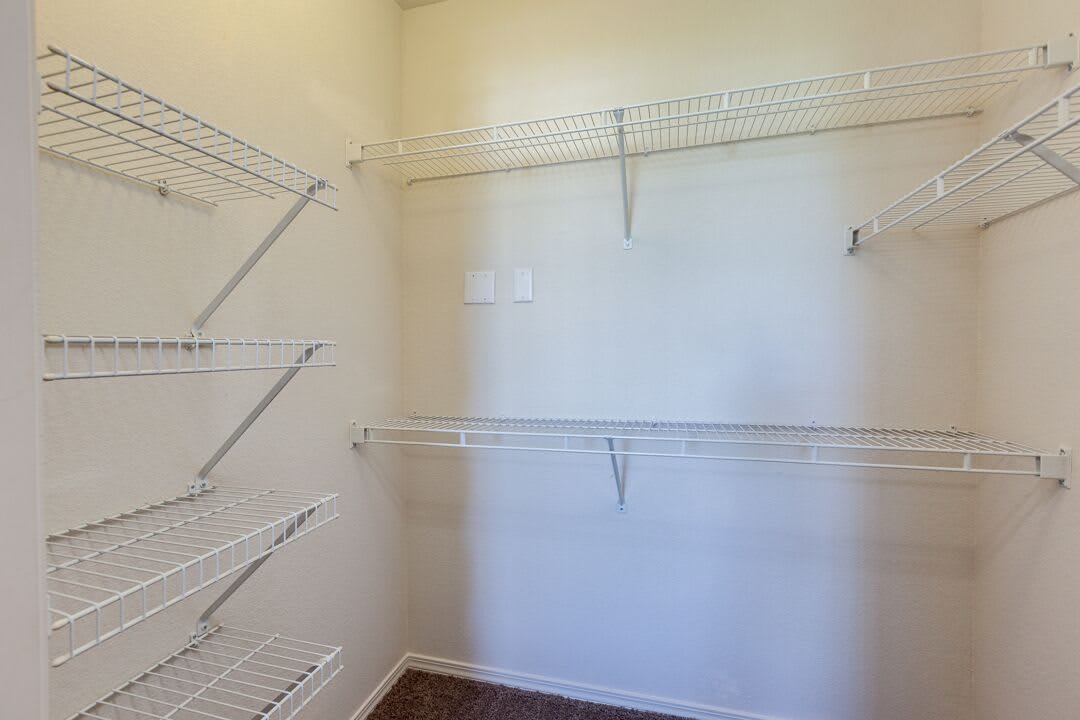 An empty closet with white wire shelves and bare walls.