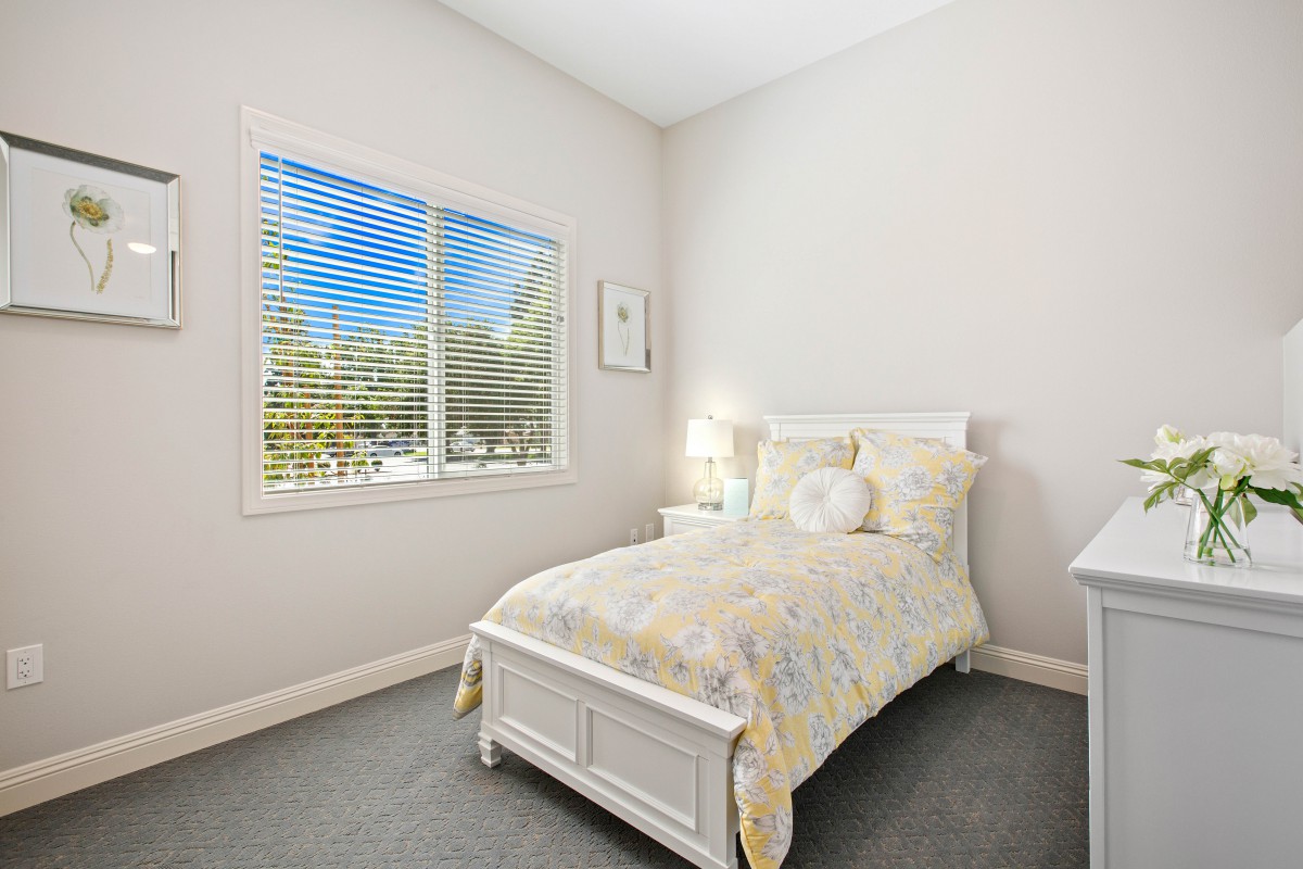 A bright and minimalist bedroom with a single bed, soft lighting, and a large window.
