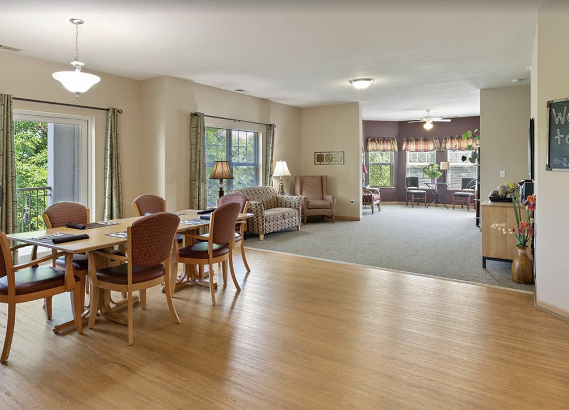 A spacious interior with a dining area and living room, featuring wooden floors and large windows.