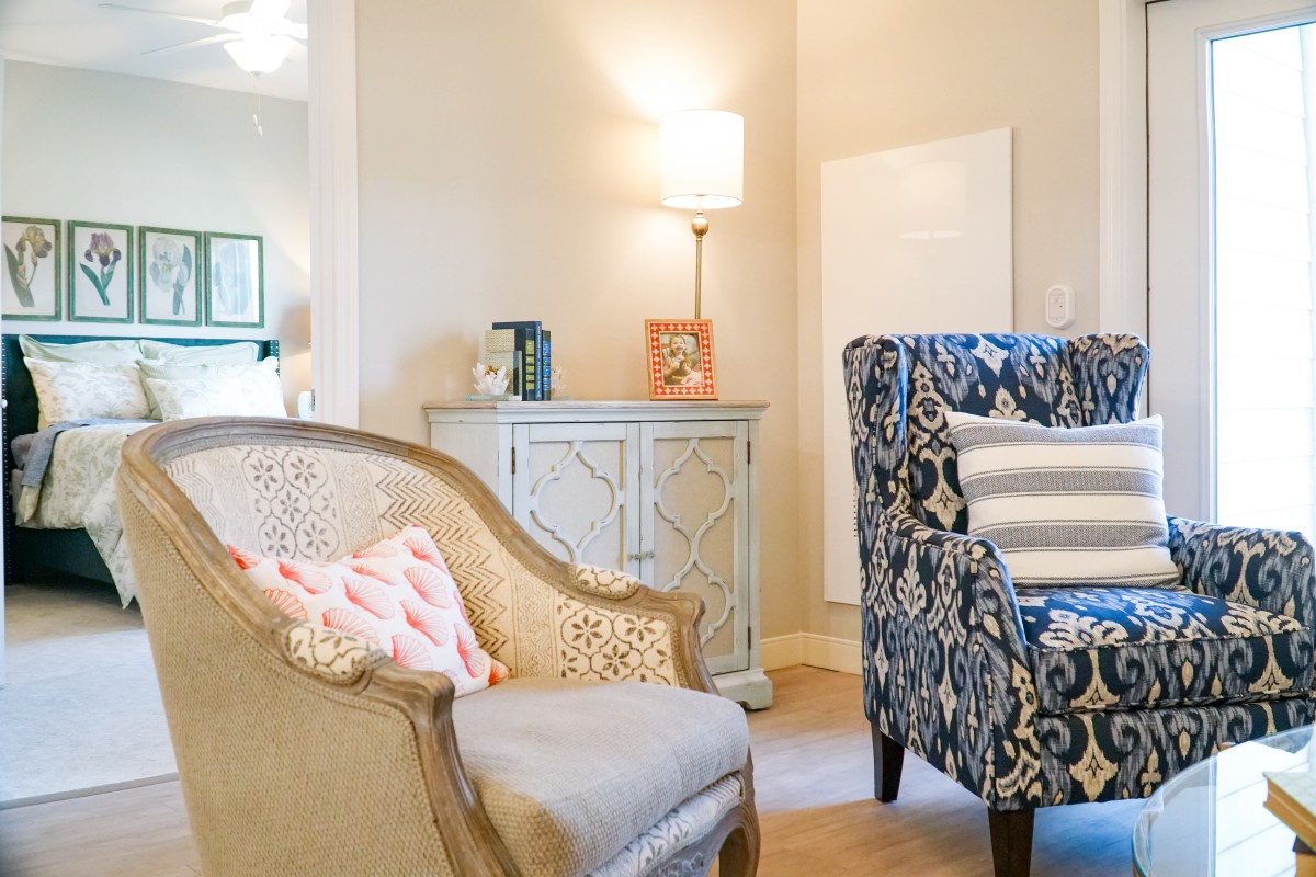 A cozy living room featuring stylish armchairs, a decorative cabinet, and a warm lamp.