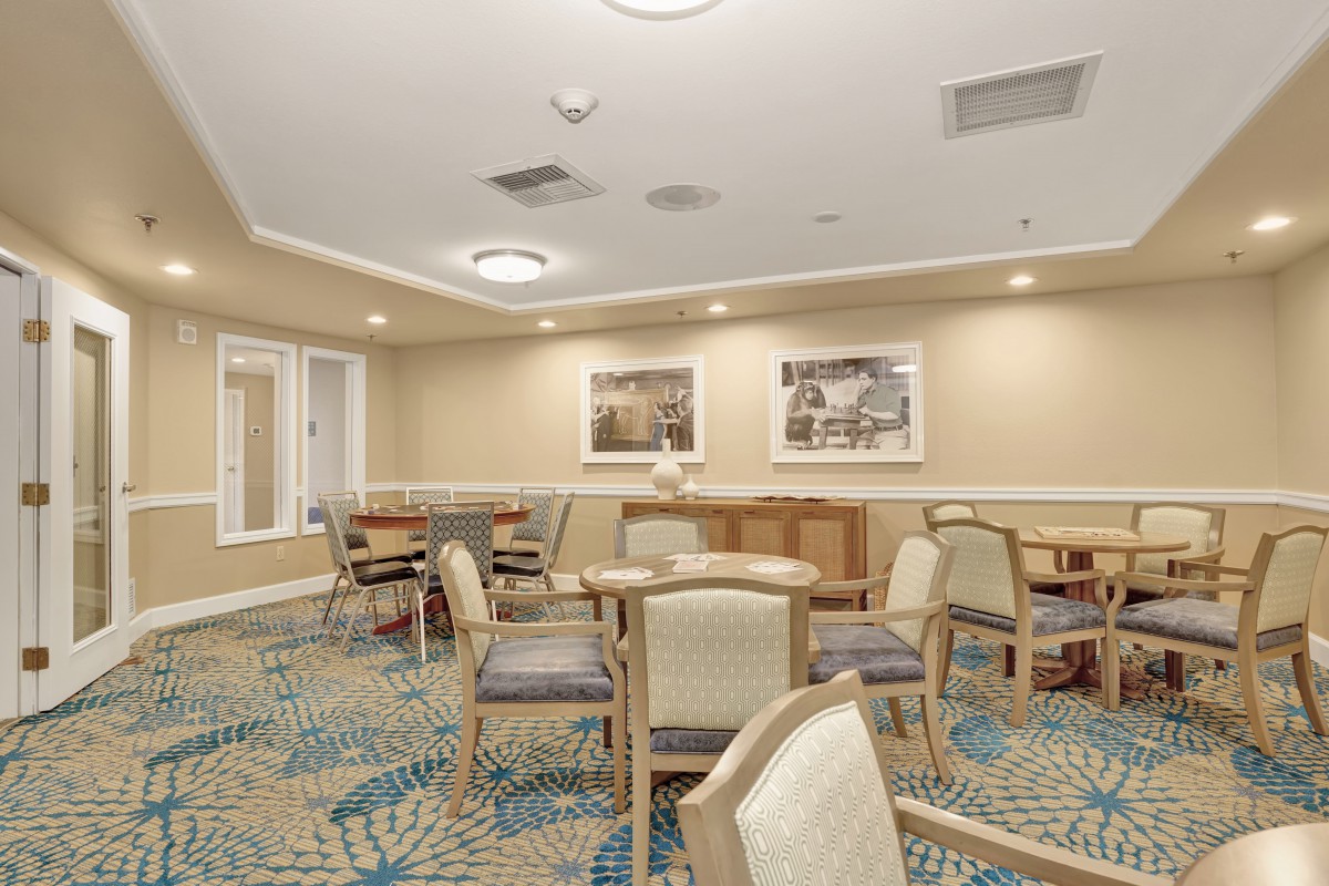 A well-lit meeting room with chairs and tables arranged on a patterned carpet, featuring decorative artwork on the walls.