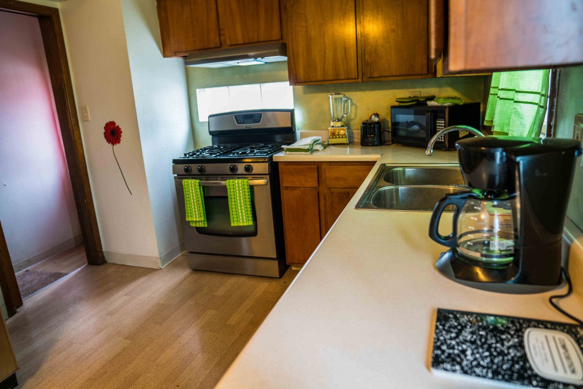 A modern kitchen with wooden cabinets, a stainless steel stove, and a double sink.