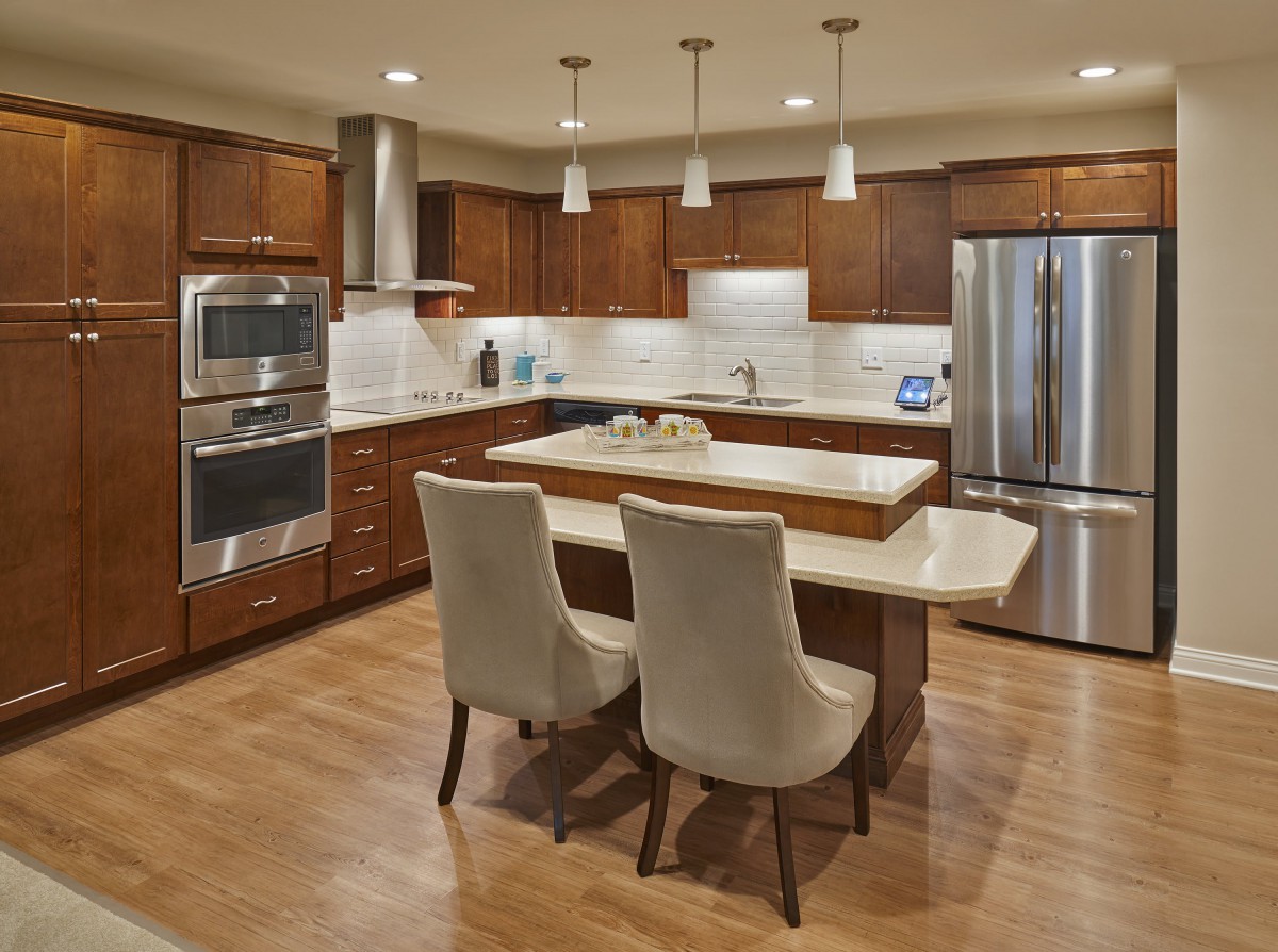 A modern kitchen with wood cabinets, a central island, and stainless steel appliances.
