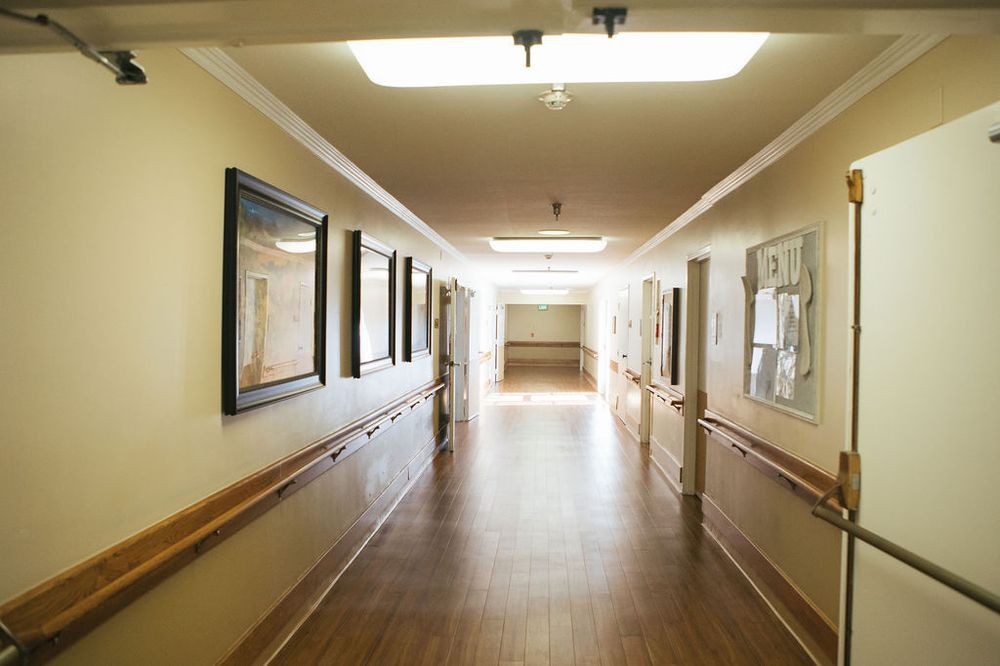 A well-lit, empty hallway with artworks on the walls.