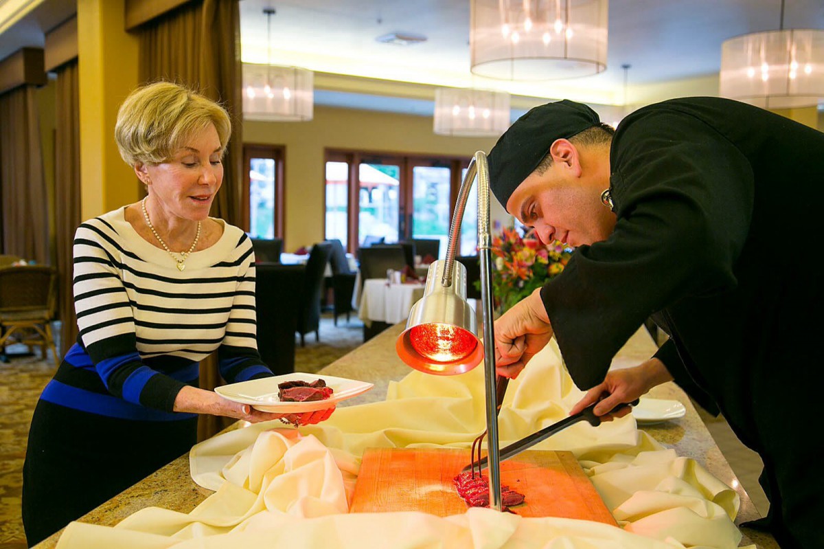 A chef serving a dish to a customer in a restaurant setting.