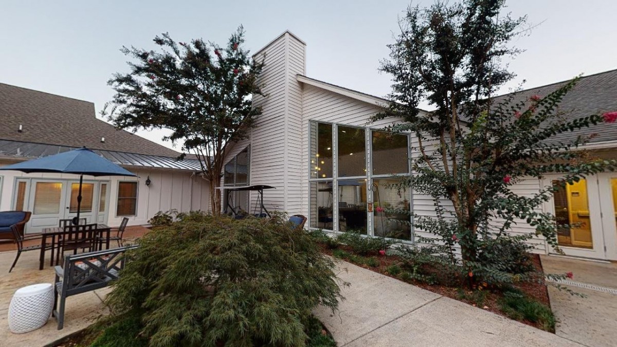 A modern house with large windows and surrounding greenery.