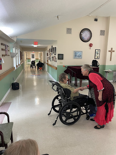 A caregiver interacts warmly with an elderly resident in a nursing home corridor, highlighting the importance of personal connections in elder care.