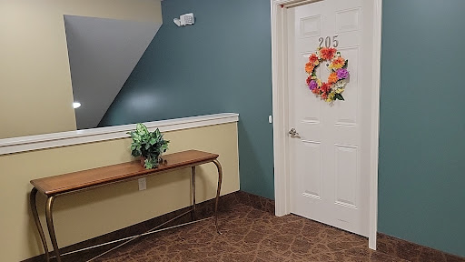 A cozy hallway featuring a welcoming door adorned with a colorful wreath and a small table with a plant.