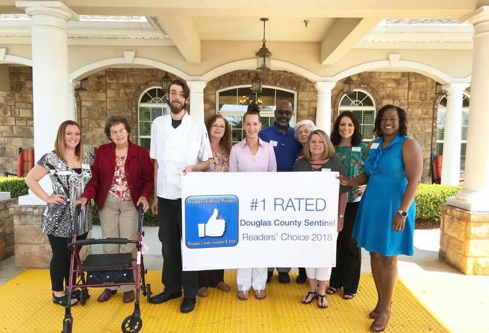 A group of people standing together holding a banner that reads '#1 Rated Douglas County Senior Services, Readers' Choice 2019'.