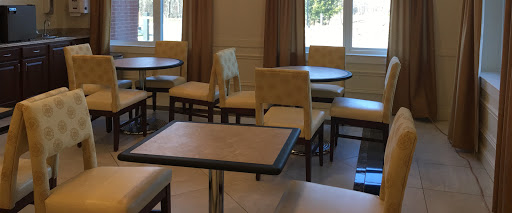 A cozy seating area featuring tables and chairs, illuminated by natural light from nearby windows.