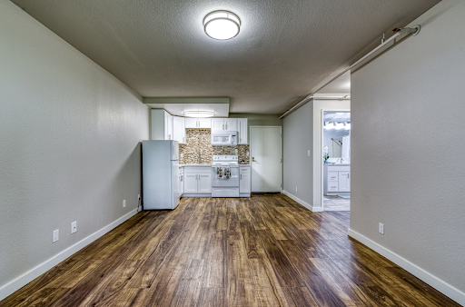 A spacious, modern kitchen area with wooden flooring and white cabinetry.