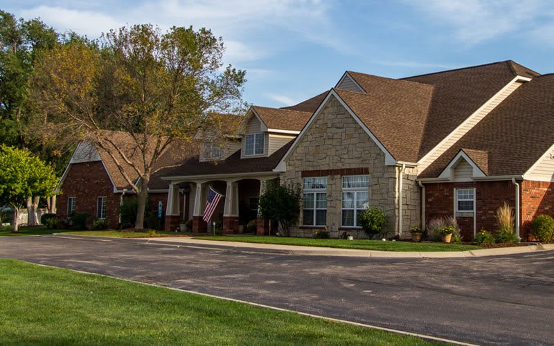 A suburban house with a well-maintained lawn and driveway on a clear day.