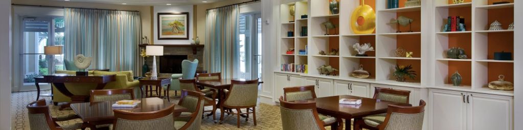A cozy dining area featuring elegant tables and chairs, with decorative bookshelves and large windows with curtains.
