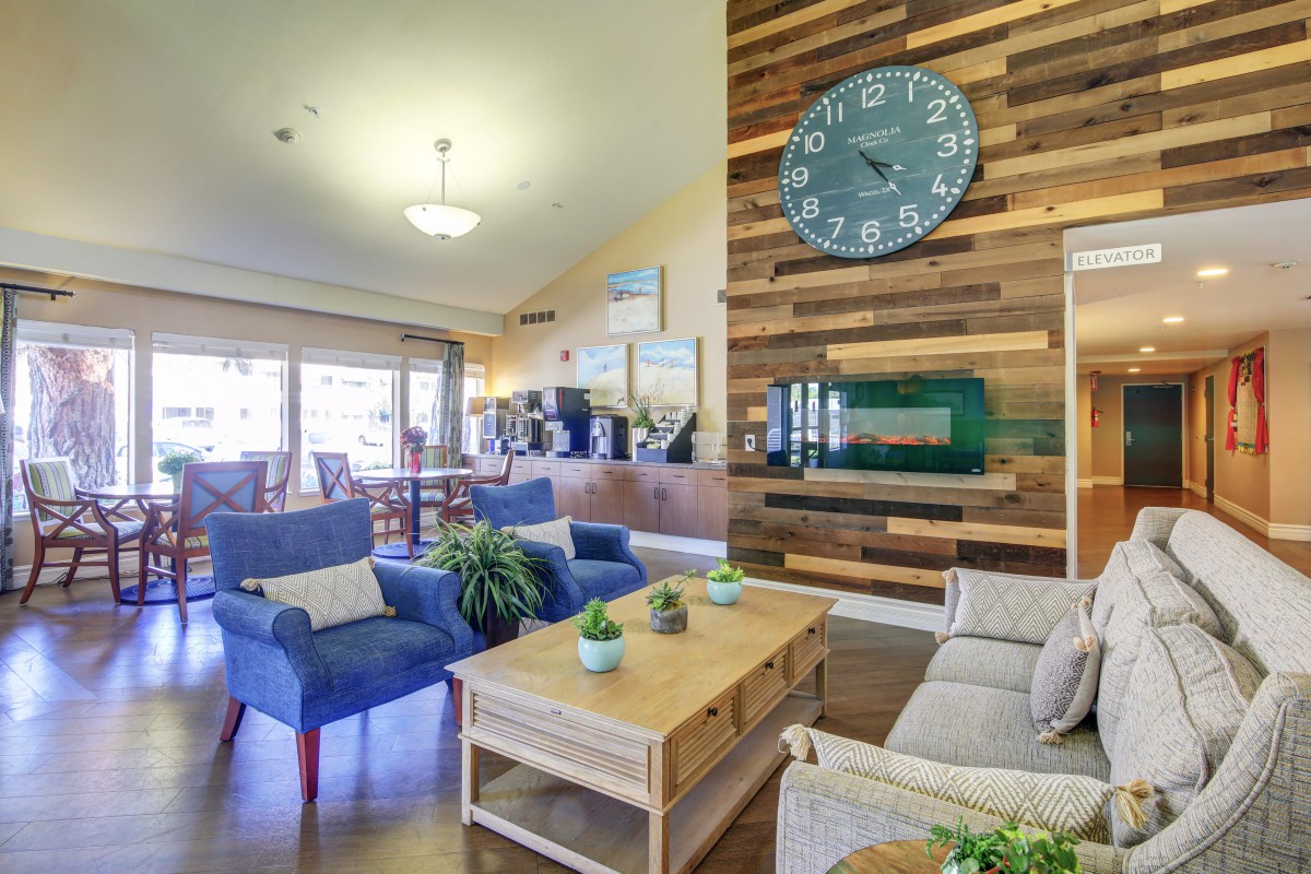 A cozy, modern living room with a wooden accent wall and a large clock.