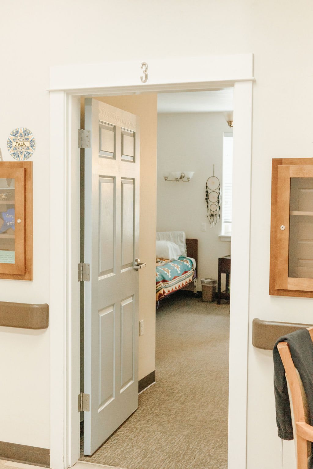 An open door leading to a hospital room with a bed and medical equipment visible inside.