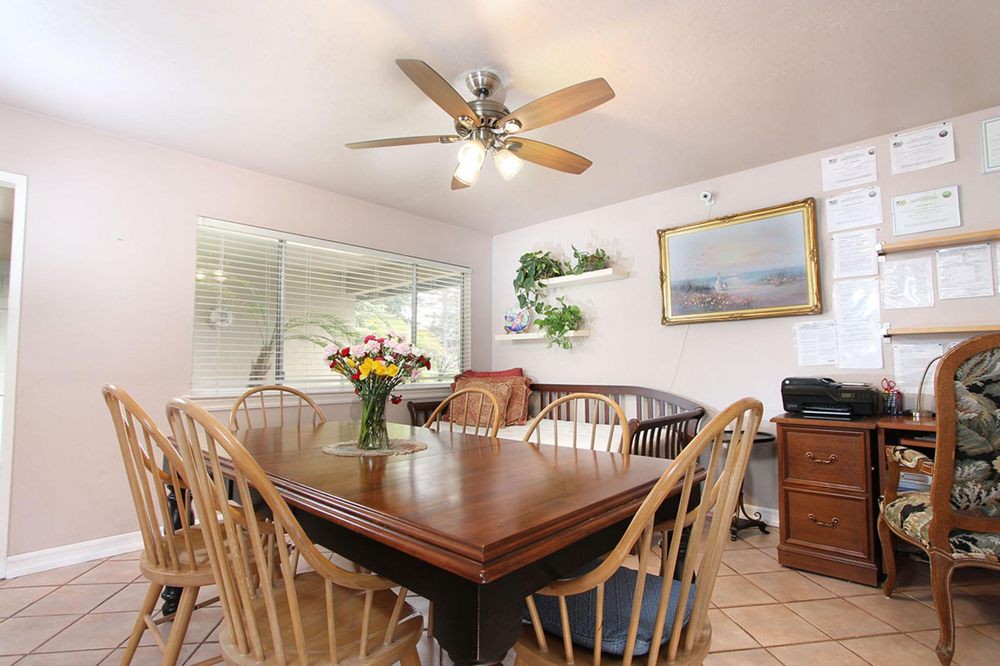 A cozy dining room with a wooden table and chairs, ceiling fan, and decorative elements.