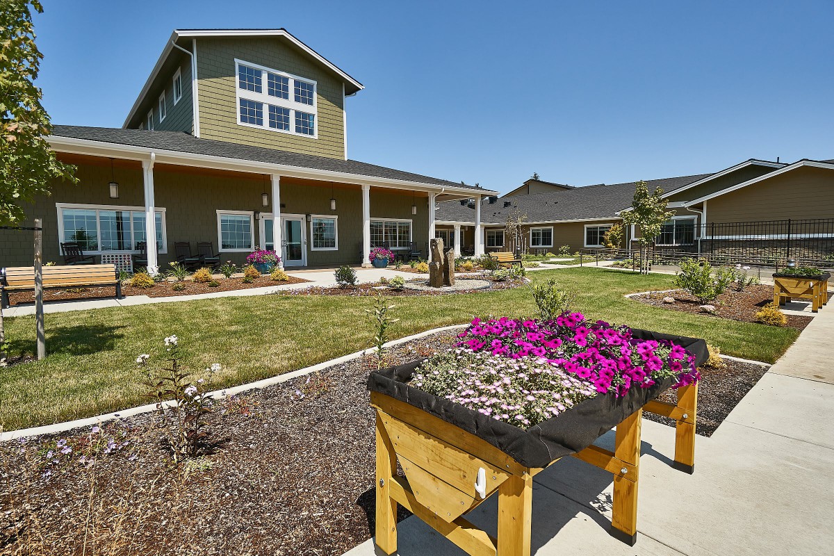 A well-maintained garden with vibrant flowers in front of a spacious house.