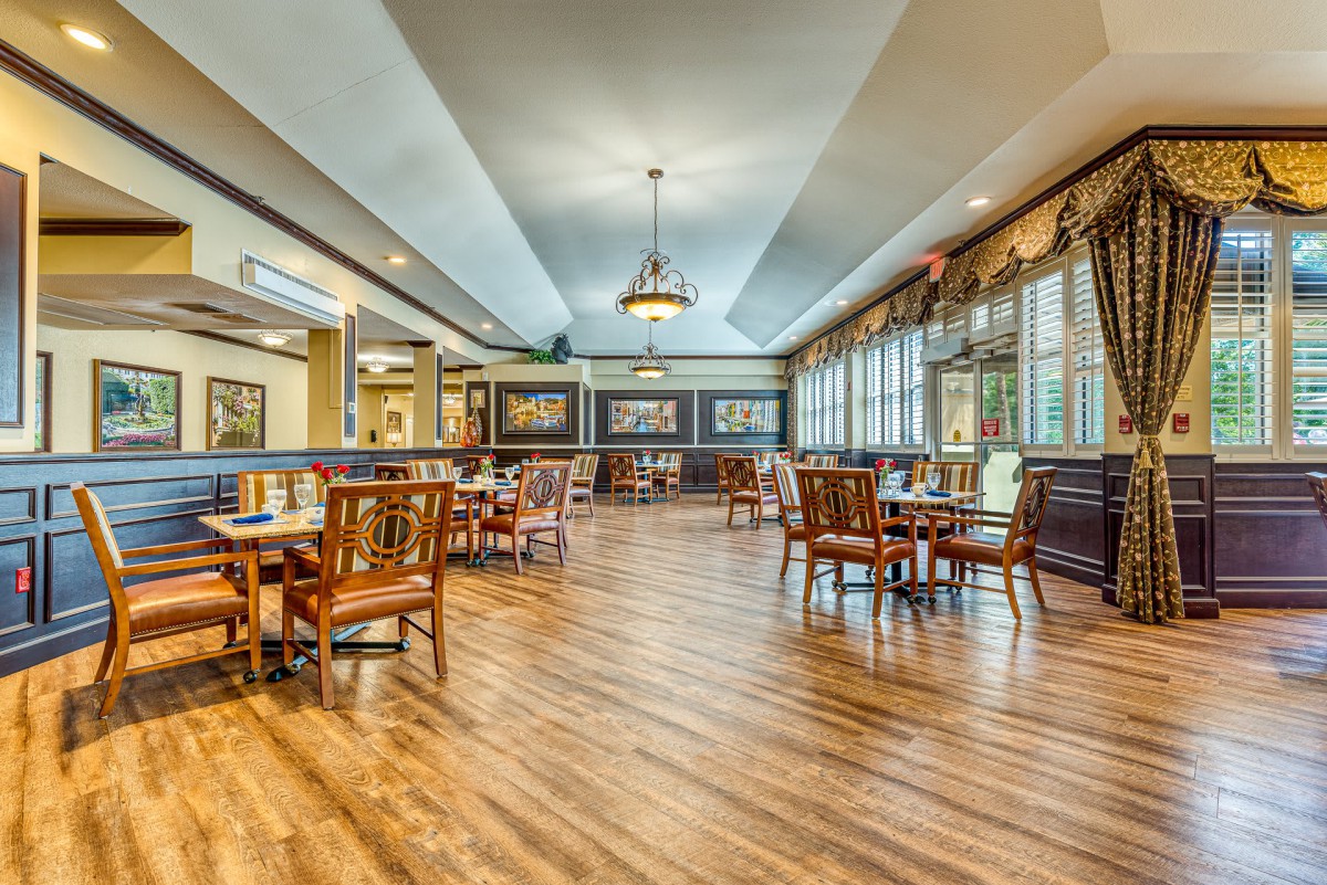 A spacious and elegantly designed dining room with hardwood floors, large windows, and sophisticated lighting.