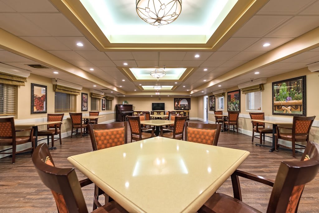 A spacious dining area with elegant lighting and neatly arranged tables and chairs.