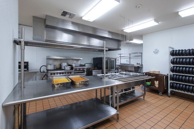 A clean and well-equipped commercial kitchen with stainless steel surfaces and industrial cooking appliances.