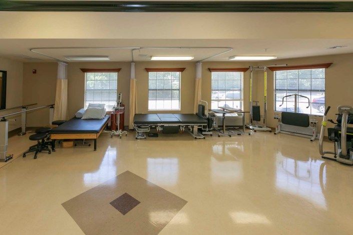A spacious physical therapy room equipped with exercise equipment and therapy tables.