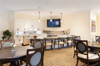 A modern kitchen and dining area featuring an island counter with pendant lighting and a television mounted on the wall.