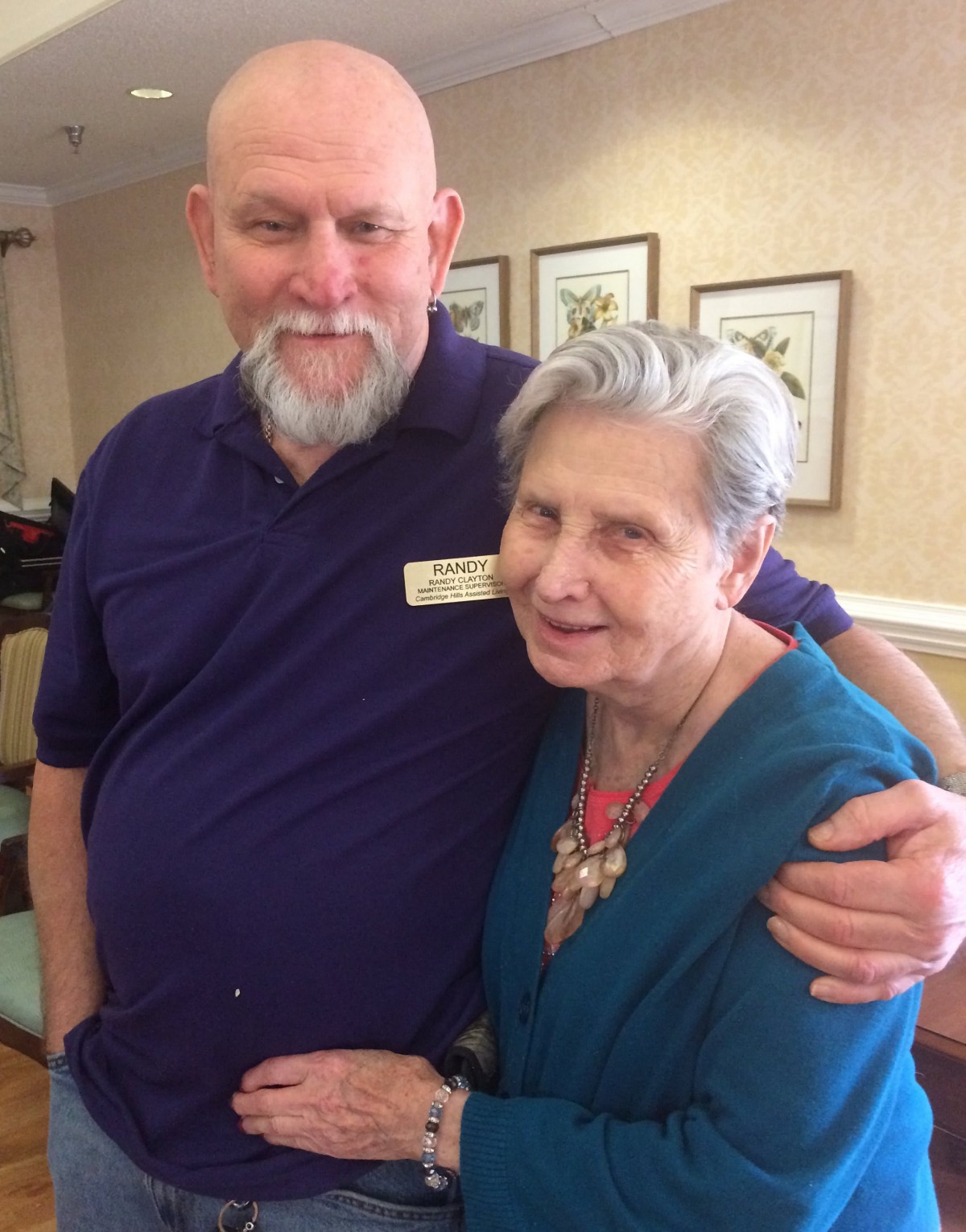An older man and woman smiling and hugging indoors.