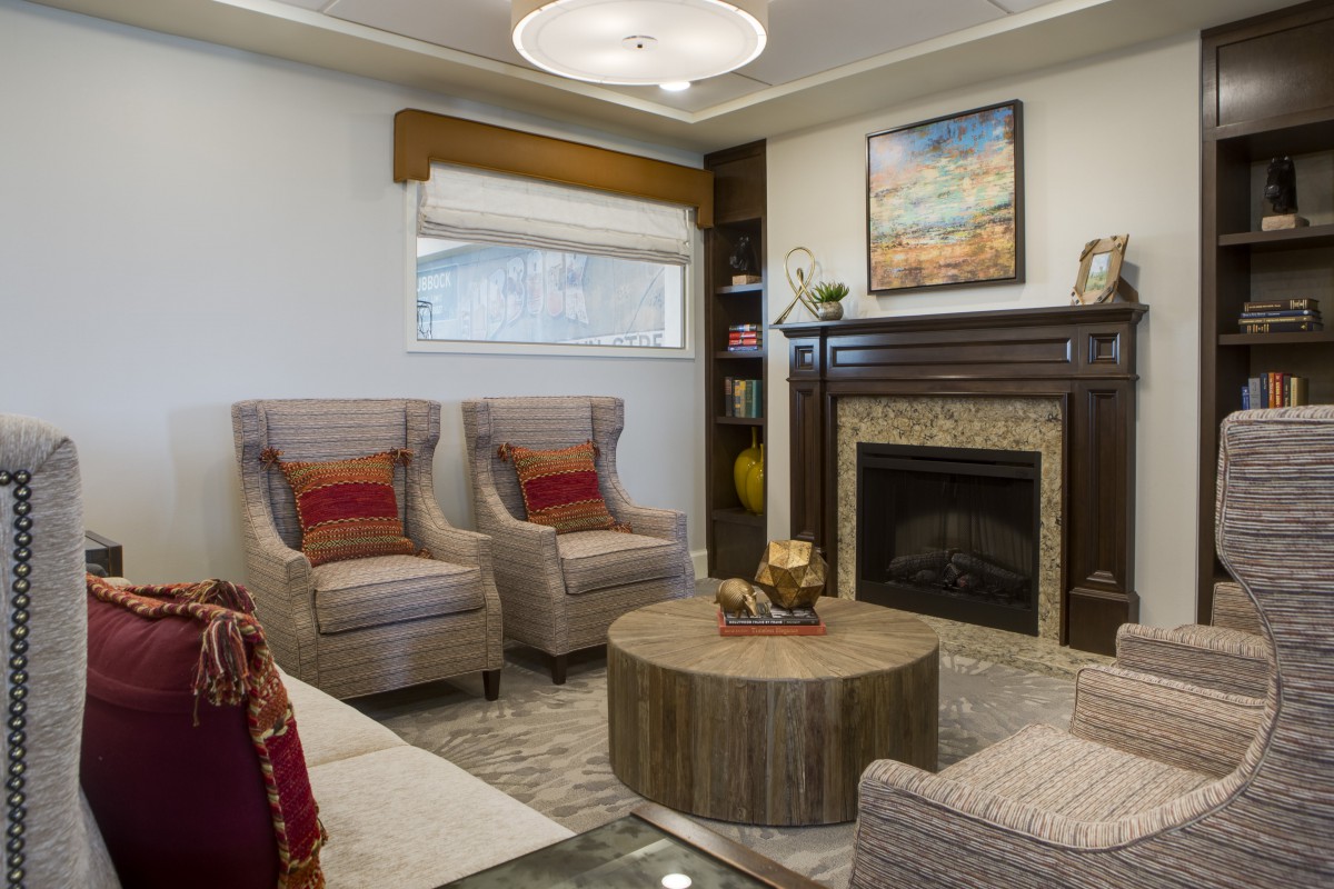 A cozy living room featuring a fireplace, armchairs, and a round coffee table adorned with decor items.